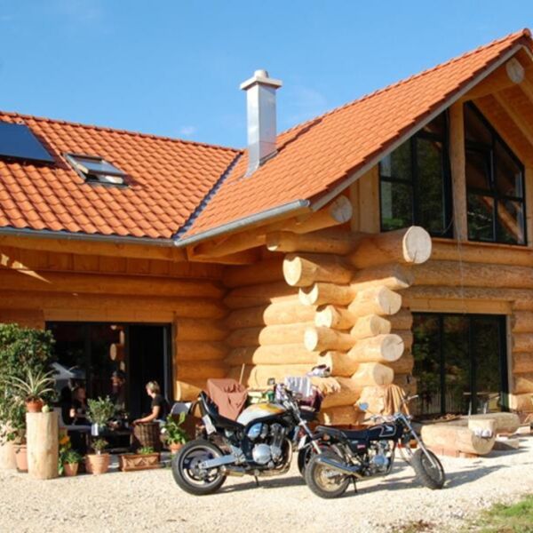 Außenansicht Naturstammhaus Blockhaus Motorrad Solaranlage