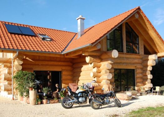 Außenansicht Naturstammhaus Blockhaus Motorrad Solaranlage